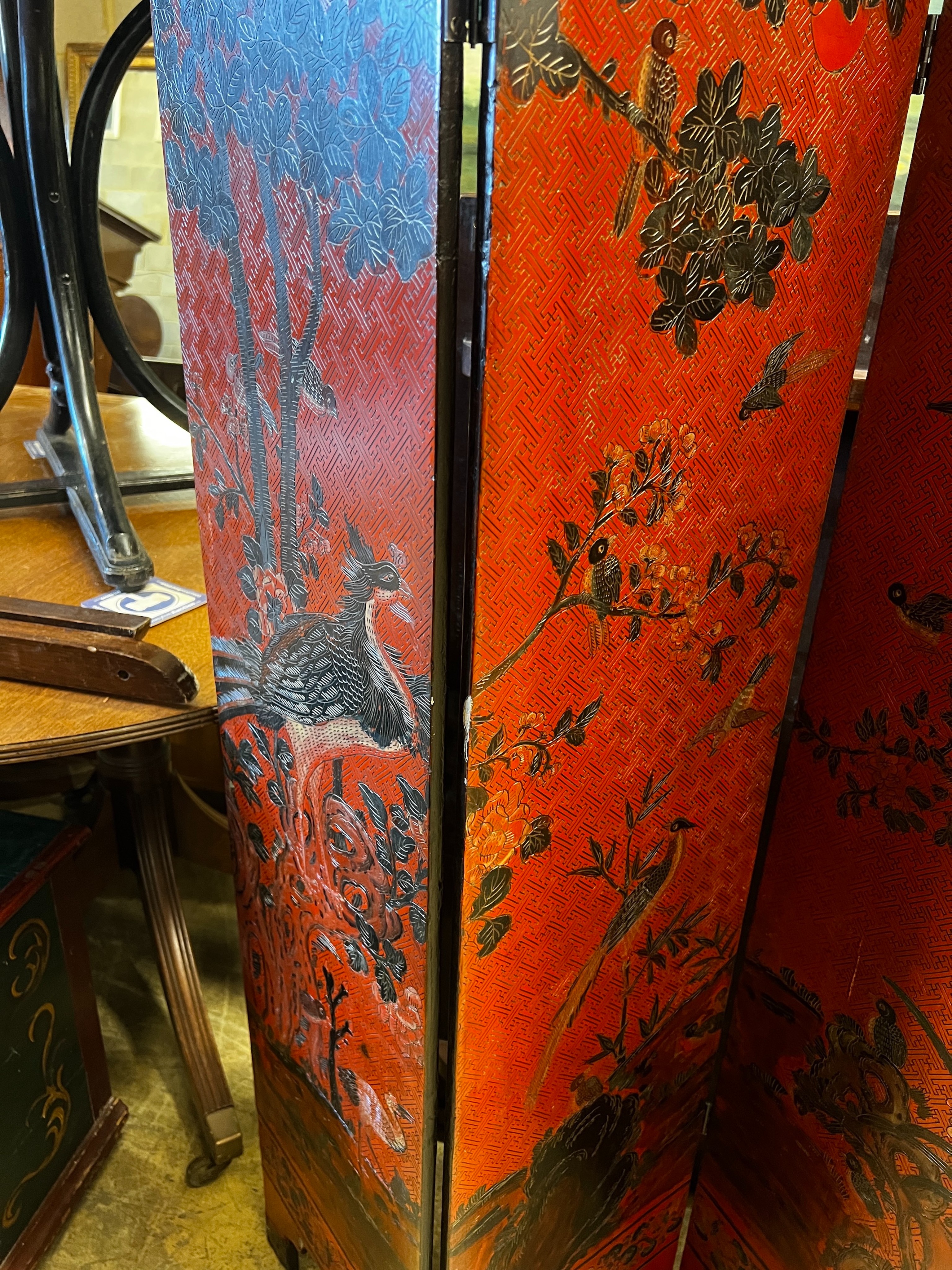 A pair of Chinese four fold lacquer screens decorated with exotic birds amongst branches, each panel width 30cm, height 141cm